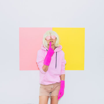 Doll Blonde Girl Model with beauty face in Fashion accessory sunglasses takes off the gloves. Mood and vibes. Minimal unicorn style. Pink and yellow neon colors. 90s or 80s trend