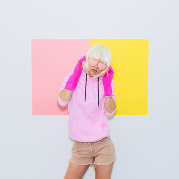 Doll Blonde Girl Model in the hood with Fashion accessory sunglasses, gloves,  hoodie and shorts.  Mood and vibes. Minimal unicorn style. Pink and yellow neon colors. 90s or 80s trend