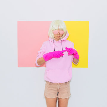 Beautiful Doll Blonde Girl Model in the hood with Fashion accessory sunglasses, gloves,  hoodie and shorts. Mood and Vibes.  Minimal unicorn style. Pink and yellow neon colors. 90s or 80s trend