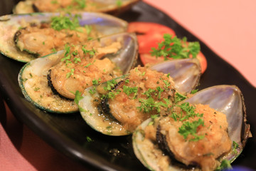 Modern Tasty oyster clams cooked well on plate and table - selective focus.