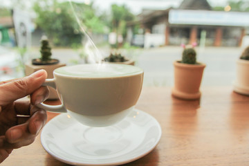 Man holding cup of green tea latte in morning at coffee shop.