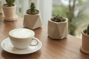 Milk green tea latte in cup on wood background