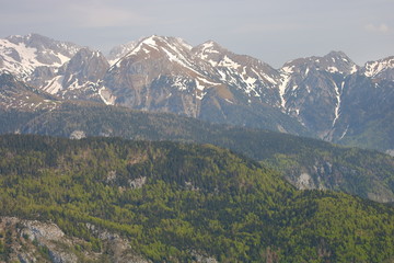 Wysokie skaliste szczyty gorskie przysypane niedużym śniegiem, poniżej łagodniejsze wzgórza  porośnięte skąpą roślinnością © Wioletta