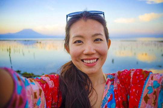 self portrait of gorgeous beautiful and happy Asian Korean or Chinese woman 20s taking selfie photo with mobile phone camera in exotic tropical beach