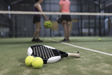 Paddle tennis objects on turf ready for tournament and women in background
