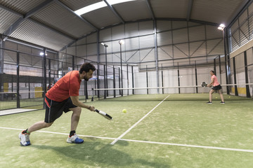 Paddle tennis player serving training with her couple in court