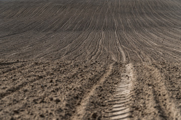 View oа a ploughed fields with a tractor tire track.