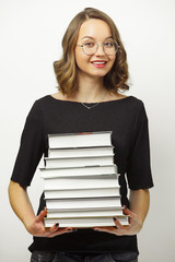 Portrait of attractive woman with stack of books in hands, has happy expression, passed the exams at the end of school or university, stands over white isolated background.