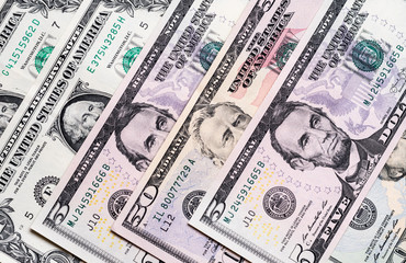US dollar bills placed evenly on plain surface 