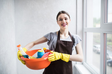 Pretty young woman holding basket of cleaning products and smiling to camera. house cleaning concept