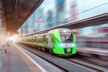 Naklejka premium Szybka jazda pociągiem z dużą prędkością na dworcu kolejowym w mieście.