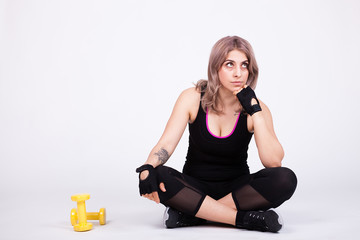 Fit woman in sport clothes lying down with two dumbbells aside her. Studio foto.