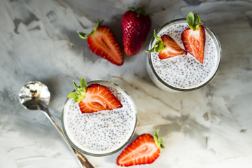 Two servings of dessert made of chia seeds, milk and strawberries on a gray table. Healthy Breakfast Concept. Top view