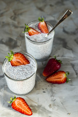 Two servings of dessert made of chia seeds, milk and strawberries on a gray table. Healthy Breakfast Concept. Top view