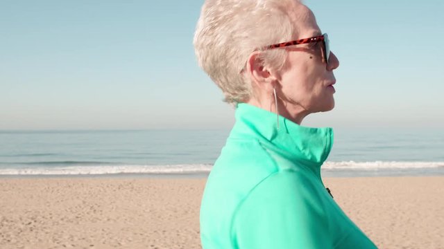 71 year old woman gets her exercise by walking along the beach.