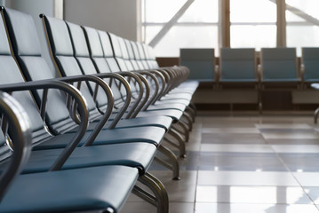 Empty airport terminal waiting area with chairs.