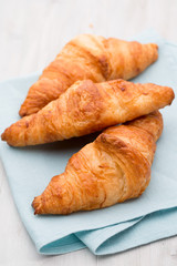 Tasty buttery croissants on old wooden table.