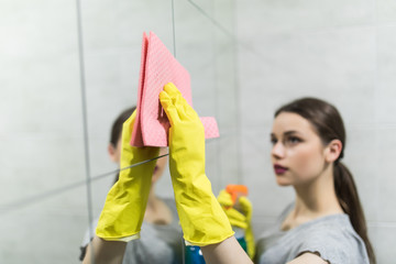 Cleaning service. Woman cleans mirror at home in bathroom.