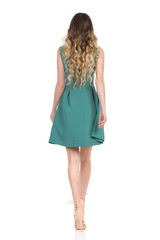 Rear View Of Walking Woman In Green Mini Dress And High Heels