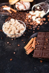 Chocolate tablets next to cinnamon rolls and other sweets and candies on a wooden background