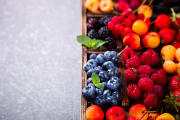 Various fresh summer Berries on the Gray Background. Mix in vintage wooden box.Food or Healthy diet concept.Super Food.Vegetarian.selective focus.Copy space for Text.