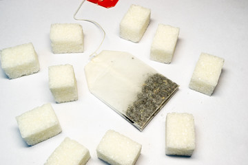 tea bags on white paper with a number of lying pieces of sugar