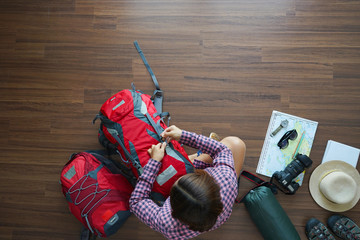 Overhead view of traveler woman plan and backpack planning vacation trip. Top view on wooden floor