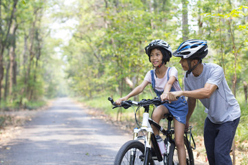 Fototapeta na wymiar Happy father and daughter cycling in the park, togetherness relaxation concept