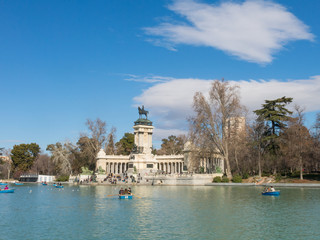Fototapeta na wymiar Beautiful picture of tourists on boats at Monument to Alfonso XII in the Parque del Buen Retiro. in Madrid, Spain