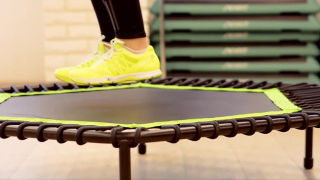 Closeup woman feet legs in sneakers on a trampoline jumping  in the gym healthy strong sport , happiness fitness fit activity 