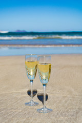 Two glasses of champagne or cava sparkling wine served on the white sandy tropical beach, luxury resort with sea view, romantic vacation