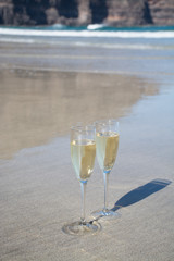 Two glasses of champagne or cava sparkling wine served on the white sandy tropical beach, luxury resort with sea view, romantic vacation