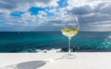 One glass of cold white wine served on outdoor terrace with sea view