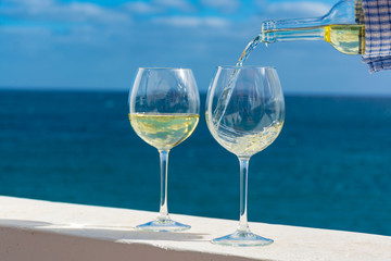Waiter pouring glass of white wine on outdoor terrace with sea view