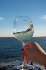 Tasting of glass of cold white wine on outdoor terrace with sea view
