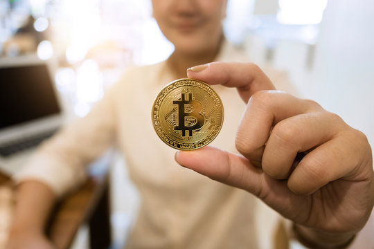 hand of woman holing golden cryptocurrency bitcoin