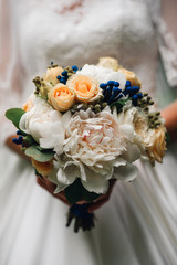 wedding bouquet of white peonies and roses in the hands of the bride