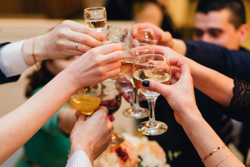 hands with wine glasses group of friends on holiday in restaurant closeup