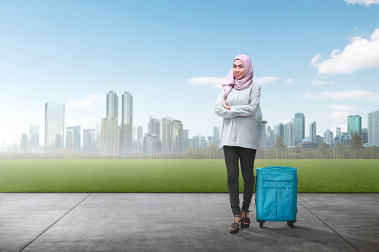 Cheerful asian muslim woman traveling with suitcase