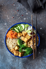 Salad with quinoa, tofu, broccoli, chickpeas and vegetables. Buddha bowl on dark background. Colorful vegetarian buddha bowl. Nourish salad bowl, table top view