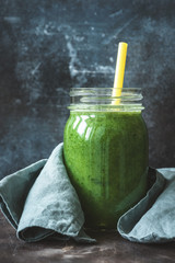 Detox green smoothie in bottle glass with drinking straw. Kale spinach green smoothie. Smoothie bottle. Cleansing, detox, diet, fitness, healthy lifestyle concept