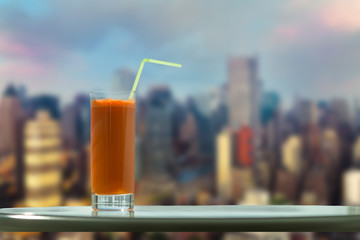 A glass of carrot juice with a straw in the cafe on the background Manhattan. New York City