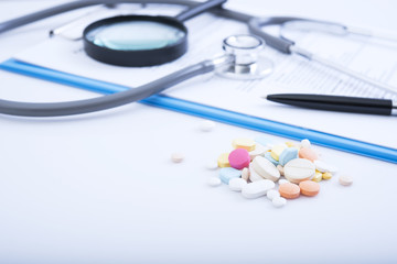 Pharmacy background on table. Stethoscope and prescription paper with colorful medicine.