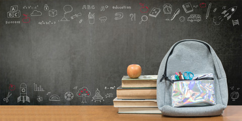 Back to school concept with school books, textbooks, backpack and stationery supplies on classroom desk with teacher's chalkboard background with educational doodle for new academic year begin