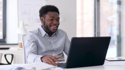 business, technology and communication concept - happy smiling african american businessman having video chat on laptop computer at office