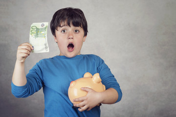 niño sorprendido con un billete de euro y una hucha cerdito