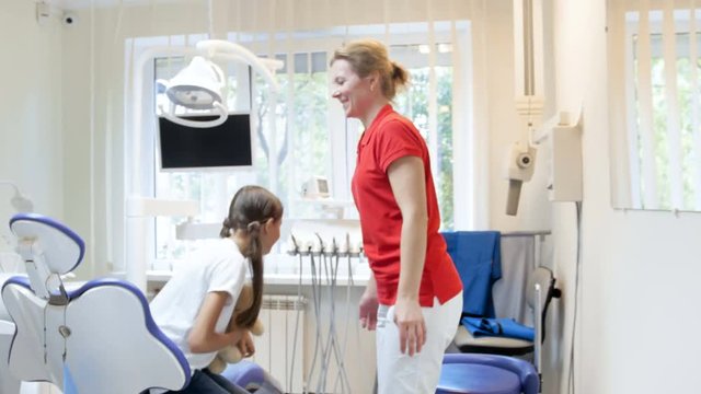 4k footage of young mother with daughter walking in dentist office for teeth checkup