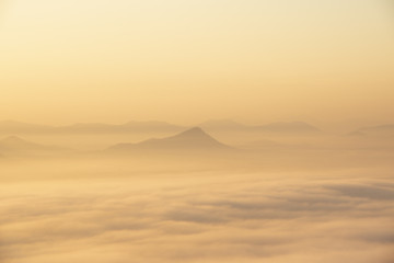 Mountain range with visible silhouettes through the early morning colorful fog.