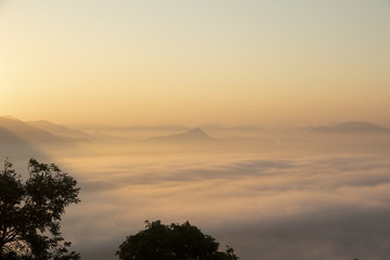 Mountain range with visible silhouettes through the early morning colorful fog.
