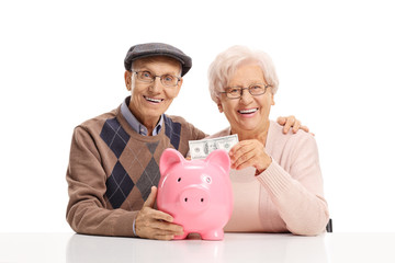 Senior couple putting money into a piggybank